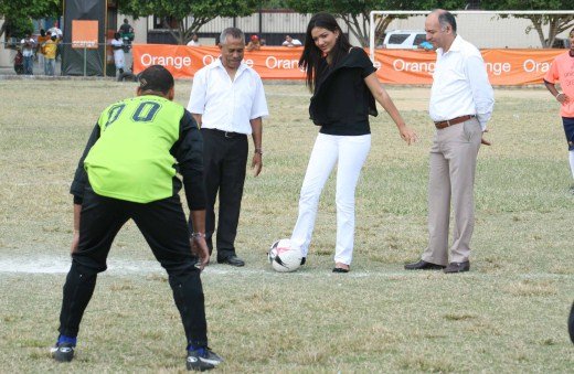 Keyla Rodríguez, Coordinadora de Relaciones Públicas de Orange Dominicana realiza el saque de honor a su lado Nelson Peña presidente de AFE y el Viceministro Santiago Cabrera.